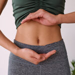 Close up of a young multi-ethnic woman's stomach cupped by her hands